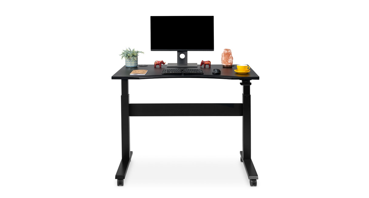 Manufacturer gallery label names the exact 48 × 30 Black Eco Curve Pneumatic desk. The image visibly shows a black curved-profile top, black frame and caster base. Monitor and staged desk objects are not package evidence; the selected grommet cover detail is not clearly established. The gallery image looks like a studio rendering/composite, but photo/render origin is uncertain.