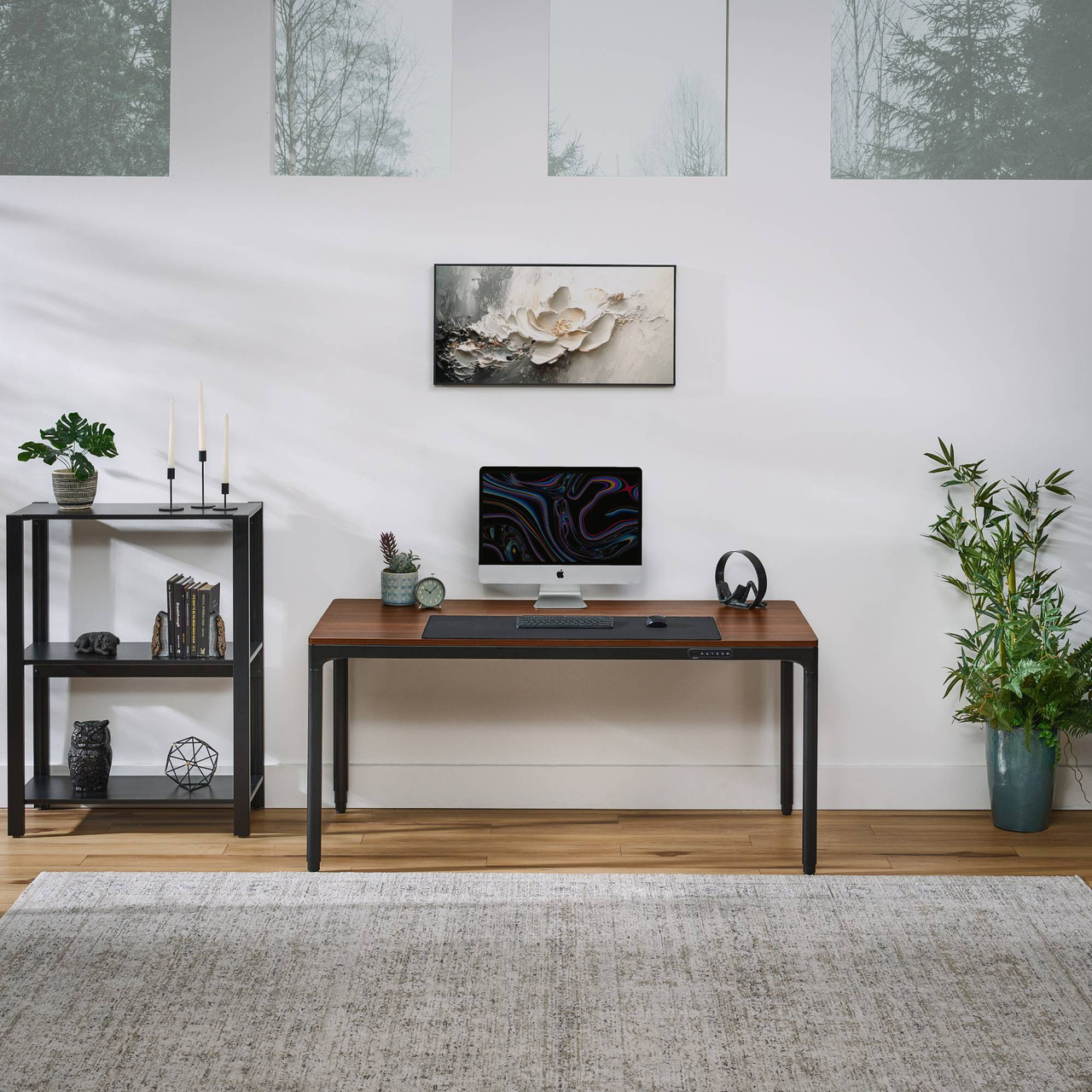 UPLIFT QuadZen UPL406 standing desk in a furnished office, with walnut-look 60 × 30-inch top, dark four-leg frame and flush front-edge keypad