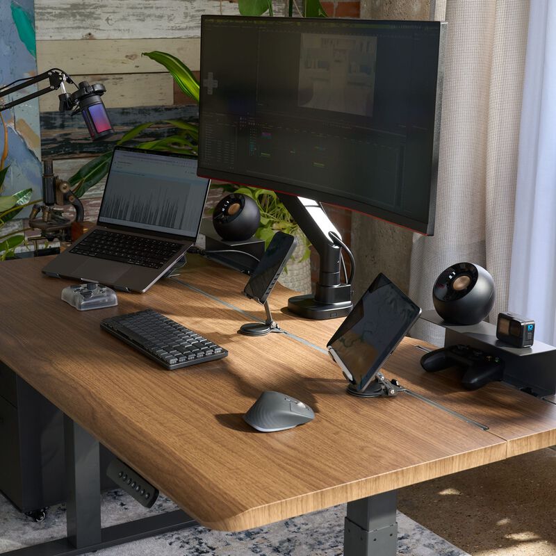 Vari Electric Standing Desk 60x30 with TechTrack in Walnut/Slate finish, shown in a staged office scene